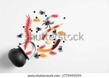 Halloween concept. Creative flat lay composition with pot and halloween candies on white background. 