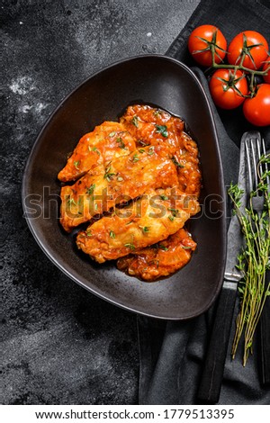 Baked halibut fish with tomato sauce. Black background. Top view