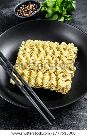 Dry, raw instant ramen noodles. Black background. Top view
