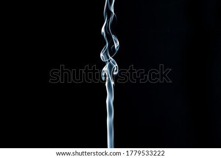 Wisps of white smoke creatively flows against a black background