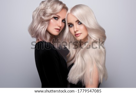 Two beautiful girls with hair coloring in blond. Stylish hairstyle curls done in a beauty salon. Beauty, cosmetics and makeup Royalty-Free Stock Photo #1779547085