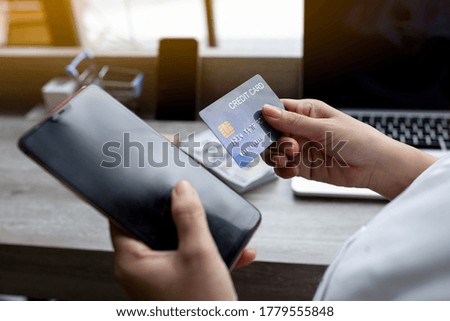 Hands holding plastic credit card and using phone. Online shopping concept. Toned picture