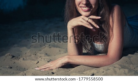 Part of the face of young woman smiling while lying on the sand, shot with copyspace on left