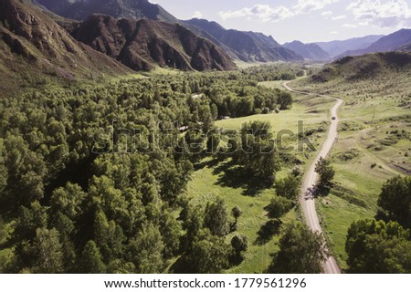 Summer mountains valley with river and mountain road. Aerial drone view