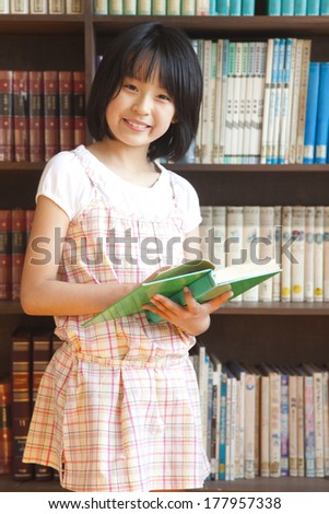 Primary Japanese girl reading a book in the library