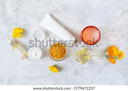 Herbal cosmetics with calendula flowers. Natural organic moisturizer cleansing product top view on grey background.
