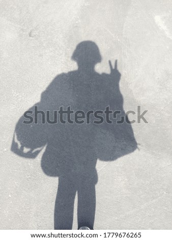 Human shadow of girl carrying bags and a helmet. 
