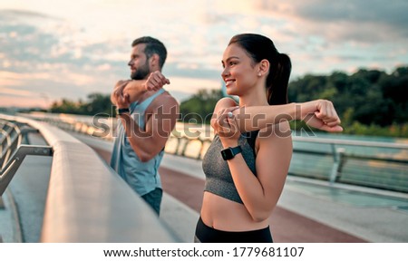 Couple stretching outdoors before morning run. Handsome bearded man and attractive sporty woman running on the street.