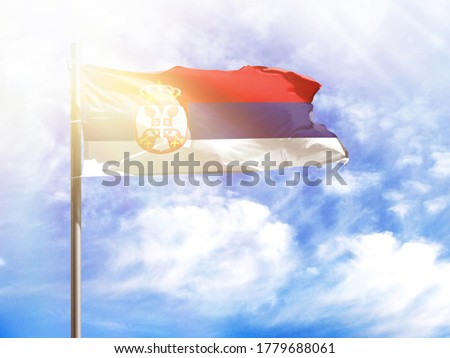 National flag of Serbia on a flagpole in front of blue sky