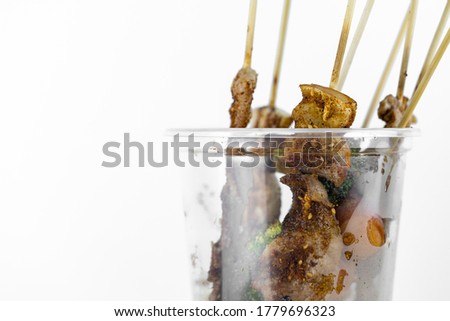 Picture of grilled pork with spicy hot Szechuan pepper sauce in plastic glasses, local street food and spicy Thai style food