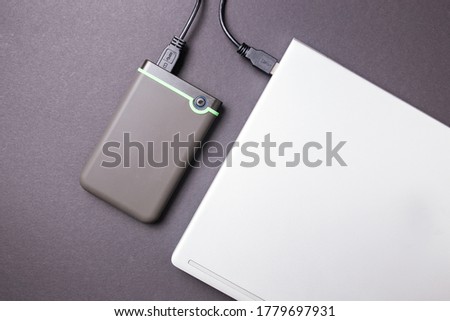 Hard disk and laptop on a black table close-up.