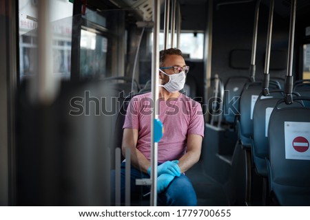 Man with medical protective mask and gloves sitting in an emtpy bus. Royalty-Free Stock Photo #1779700655