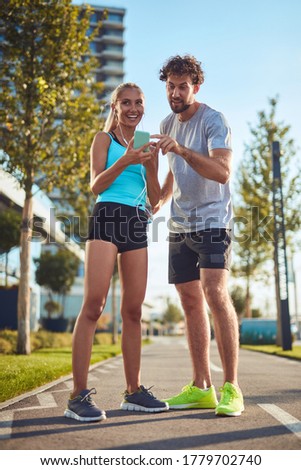 Modern couple making pause on the sidewalk during jogging / exercise.