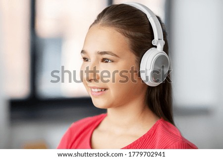 children and technology concept - portrait of smiling teenage girl in headphones listening to music at home