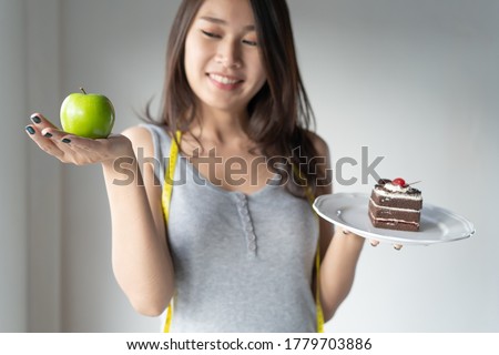 Choose right food for you health. Person eat dessert holding green apple and cake to compare calories as sweet menu to eat during diet. Royalty-Free Stock Photo #1779703886
