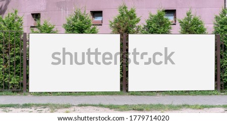 two big white empty banners hanging on metal fence outside with blank mock-up for commercial information rental housing concept