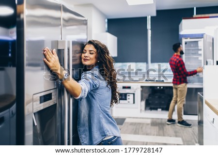 Young couple, satisfied customers choosing fridge in appliances store. Royalty-Free Stock Photo #1779728147