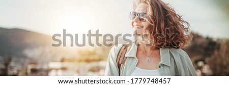 Portrait of a beautiful young smiling curly woman in the sun outdoor, panormama banner format.