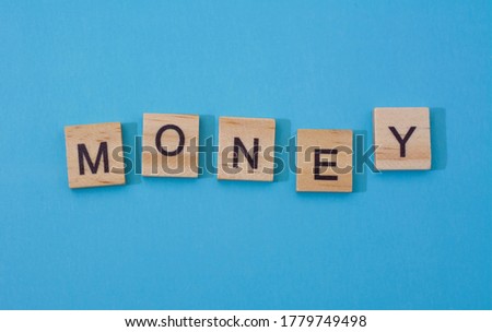 The word money. The text of the wooden letters.Black letters on wood, blue background with shadows. blank for design