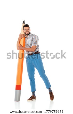 Positive nerd in eyeglasses embracing big pencil on white background
