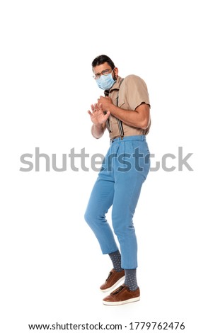 Scared nerd in eyeglasses and medical mask showing stop gesture isolated on white