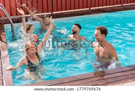 Young people having fun in villa exclusive party inside swimming pool - Happy friends enjoying summer time - Holidays and friendship concept - Main focus on close-up couple