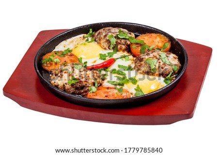 fried eggs with meat and red pepper baked in a pan, top view, cut-out picture on a white background