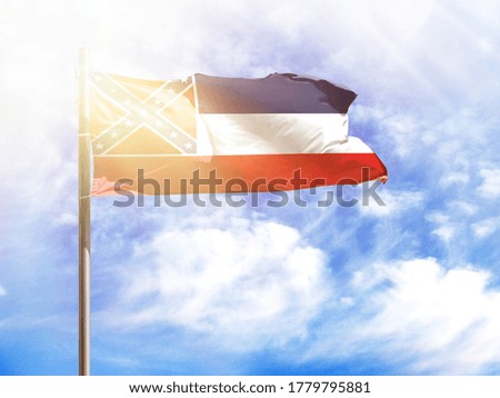 National flag of State of Mississippi on a flagpole in front of blue sky