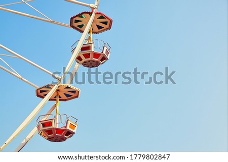 Retro toned close up picture of two Ferris wheel cars with cloudless sky, space for text.
