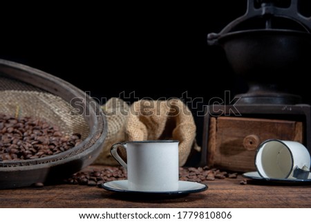
Roasted coffee on rustic wood, cup, grinder and more with black background, selective focus