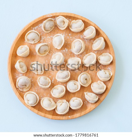 Raw pelmeni or russian dumplings on a wooden plate. Top view. Royalty-Free Stock Photo #1779816761