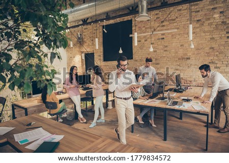 Nice confident experienced people director calling employee discussing document analysis at modern industrial loft brick open space style interior workplace workstation Royalty-Free Stock Photo #1779834572