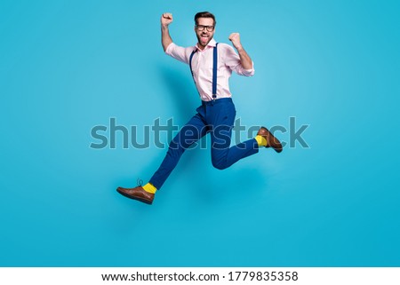 Full body profile photo of handsome man jump high up running competition work worker raise fists first place winner wear specs shirt suspenders pants boots isolated blue color background Royalty-Free Stock Photo #1779835358