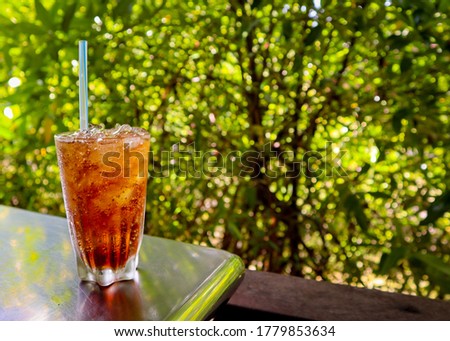 Cool ice soft drink cola carbonated liquid on the table with natural background.