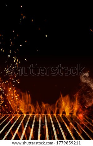 Empty steel barbecue BBQ grill grate with flaming fire, sparks and smoke on black background. Cooking concept. Close up, copy space
