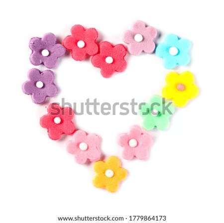 Decorative flower shaped cake topping candy sprinkles arranged as heart isolated on white background, top view 