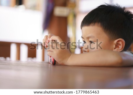 Asian boy about 3 year and 10 months addict and keep using mobile phone for watching cartoon application