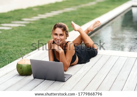 Woman freelance work typing on laptop poolside outdoors with fresh coconut . Traveling with a computer wifi always in toch, dream life concept.
