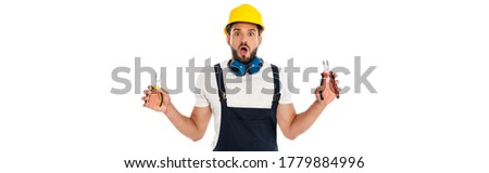 Panoramic shot of shocked repairman in uniform holding pliers isolated on white