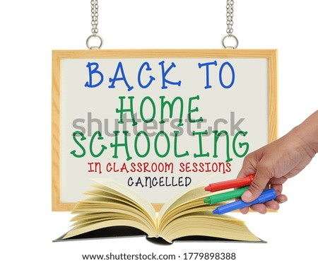 Back To Home Schooling In Classroom Sessions Cancelled white board sign behind open book and hand with markers