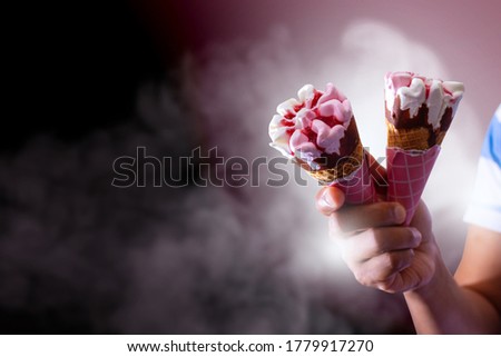 delicious strawberry and cream ice cream, with strawberry sauce inside and on topping, holding ice cream, two, backgrounds, photography