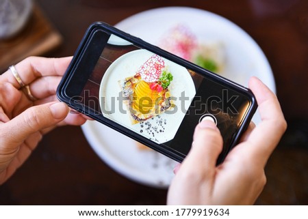 Food photography woman hands make photo cake with smartphone / taking photo food for post and share on social networks with camera smart phone in restaurant 