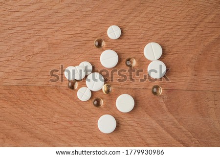 A bunch of various medicines, pills lying around without packaging, on a wooden board