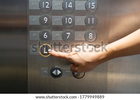 The hand presses on the lobby floor elevator button in hotel