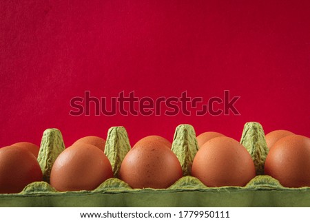 Eggs, raw brown chicken eggs in green box, on a red background.