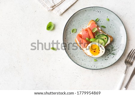 Healthy open salmon sandwich with cream cheese, soft egg, veggies and greens. Delicious protein fish sandwich for breakfast or brunch, top view, copy space. Royalty-Free Stock Photo #1779954869