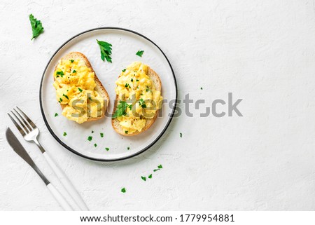Scrambled Eggs on toasted bread for healthy breakfast or brunch on white background, top view, copy space.  Royalty-Free Stock Photo #1779954881