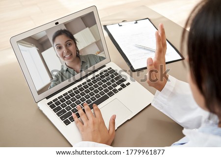 Female doctor gp consulting indian woman patient make online webcam video call on laptop screen. Telemedicine conference remote computer virtual visit in zoom meeting. Over shoulder videocall view. Royalty-Free Stock Photo #1779961877