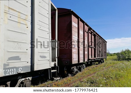 Rail cars on rails. Pictured along. Clear skies and a sunny day. A horizontal perspective.