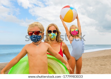 Funny children in sunglasses, inflatable toys on tropical sea beach. New rules to wear cloth face covering mask at public places due coronavirus COVID 19. Family holidays with children, summer travel